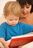 Frau mit einem Kind, das eine Gutenachtgeschichte liest