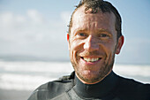 Lächelnder Surfer steht am Strand