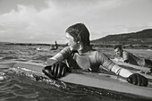 Jugendlicher im Meer, der sich an seinem Surfbrett festhält