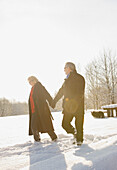 Älteres Paar geht händchenhaltend durch den Schnee