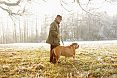 Profil eines reifen Mannes, der mit einem Hund im Park spazieren geht