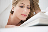 Frau liegt im Bett und liest ein Buch