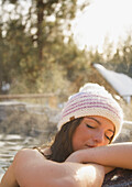 Junge Frau ruht sich mit geschlossenen Augen auf dem Rand eines Whirlpools aus