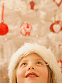 Nahaufnahme eines Mädchens mit einer pelzigen Weihnachtsmütze, das nach oben schaut