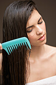 Woman combing her hair with a wide tooth comb