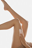 Frau trägt Körperlotion auf den Beinen auf