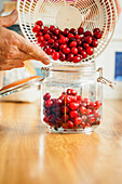 Man Pouring Cherries in a Mason Jar, Close-up view