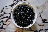 View from above still life black chokeberries in bowl on granite counter