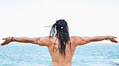 Back View of Man Facing Ocean with Arms Wide Open