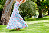Frau in geblümtem Kleid tanzend im Garten