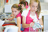 Young girls in cookery class washing up