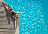 Elevated view of a woman sunbathing on the edge of a swimming pool