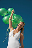 Woman holding a bundle of green balloons smiling - low angle view