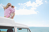 Girl Sightseeing from Camper Van Rooftop with Binoculars