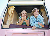 Junge und Mädchen schauen aus dem Heckfenster eines Wohnmobils