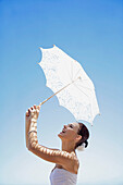 Bride Holding Parasol against Blue Sky