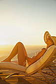 Frau beim Sonnenbaden auf einem Liegestuhl bei Sonnenuntergang