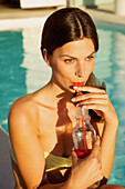 Woman Drinking with Straw by Swimming Pool