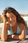 Smiling Young Woman Sunbathing on Deck