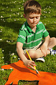 Junge bemalt Pappausschnitt im Garten