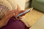 Nahaufnahme Hände einer älteren Frau, die ein Smartphone benutzt