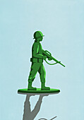Grüner Soldat mit Gewehrspielzeug auf blauem Hintergrund