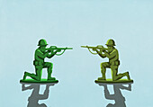 Toy soldiers with rifles face to face on blue background