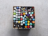 Flat lay multicolored markers and paint cans in box