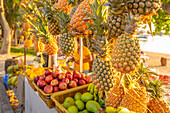 View of pineapples and apples on fruit stall in Grand Bay at golden hour, Mauritius, Indian Ocean, Africa