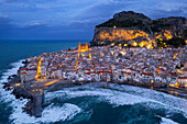 Das beleuchtete Fischerdorf Cefalu mit dem Felsen auf der Spitze der Altstadt von der Drohne aus gesehen in der Abenddämmerung, Cefalu, Provinz Palermo, Tyrrhenisches Meer, Sizilien, Italien, Mittelmeer, Europa