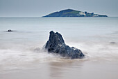 Blick in der Abenddämmerung auf die Felsen am Strand von Bantham, mit Blick auf Burgh Island und sein Hotel, an der Südküste von Devon, England, Vereinigtes Königreich, Europa