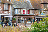Touristen sitzen in einem Café in dem normannischen Dorf Beuvron-en-Auge, Beuvron-en-Auge, Normandie, Frankreich, Europa