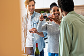 Friends toasting with wineglasses during reunion in kitchen