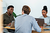 Gruppe von Geschäftsleuten, die in einem Büro sitzend ein Projekt besprechen