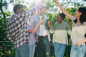 Group of friends toasting with beer bottles standing outdoors