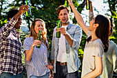 Group of friends toasting with beer bottles standing outdoors