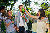 Gruppe von Freunden stößt im Freien stehend mit Bierflaschen an
