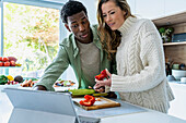 Ehepaar sieht sich ein Kochrezept auf einem digitalen Tablet an, während es an der Küchentheke steht