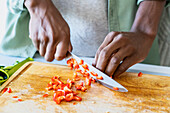 Nahaufnahme von Männerhänden beim Schneiden von Gemüse mit einem scharfen Messer auf einem Schneidebrett
