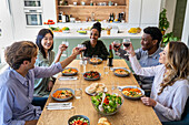 Gruppe von Freunden stößt während eines Abendessens mit Weingläsern an