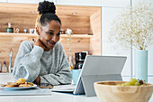 Woman having a web conference on digital tablet in kitchen