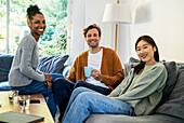 Small group of friends gathered in living room looking at the camera