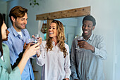 Gruppe von Freunden, die mit Weingläsern in einem häuslichen Raum anstoßen