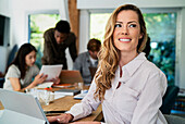 Female financial assistant looking up while sitting using digital tablet