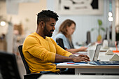 Afroamerikanischer Mann arbeitet mit Laptop im Büro
