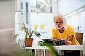 Adult male designer leaning on table while reading magazine