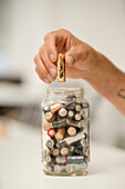 Close up of human hand separating batteries on glass jar
