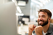 Male entrepreneur celebrating while watching at computer monitor