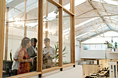 Wide view of businessmen and businesswomen discussing while standing behind window