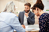 Adult couple signing contract during meeting with male lawyer